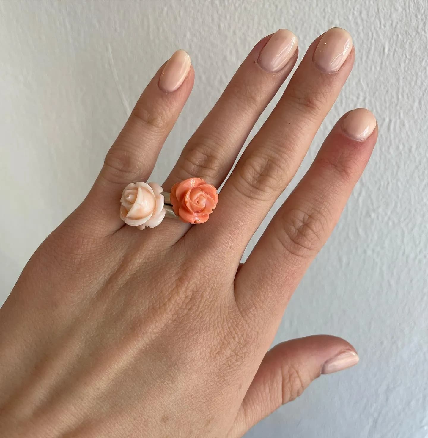 Hand mit rosafarbenem Ring und Korallenring